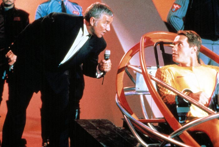 Så er reality-tv-programmet i gang. Richard Dawson er værten Killian, og det er Arnie i den varme stol i 'The Running Man' (1987).