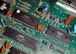 Udsnit af printpladen inde i en Commodore 64, med nogle af de vigtige MOS-chips. CPU'en (MOS 6510) er den aflange chip nederst til venstre i billedet. 64'erens legendariske lydchip, SID (MOS 6581), er den øverste chip til højre. Foto: Wikimedia Commons.