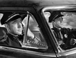 Peterson (Whitmore) og Blackburn (Ed Drake) i patruljevognen ved filmens begyndelse.